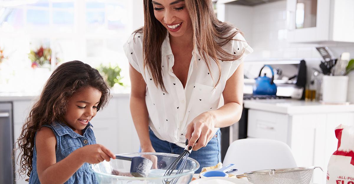 young girl and mother measuring ingredients to make a cake in the kitchen
