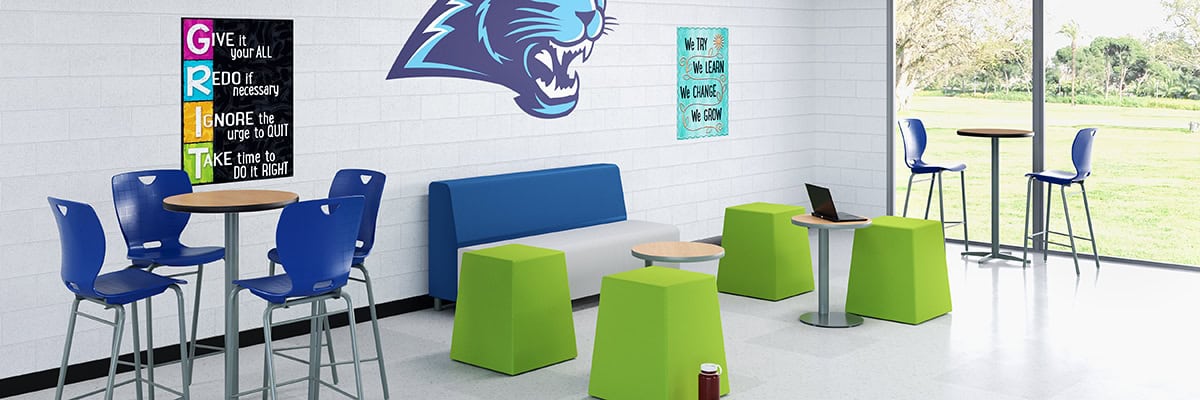 school hallway with floor to ceiling window, soft seating options, and high cafe tables with chairs