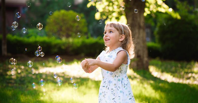 little girl playing with bubbles outside