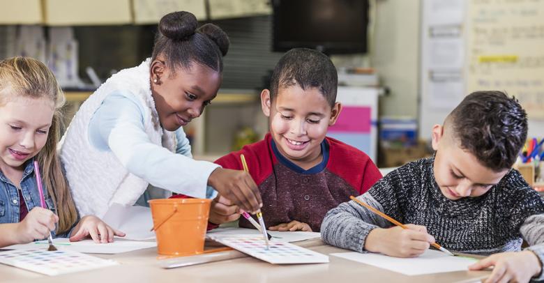 four young students painting an art project together