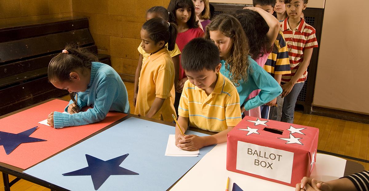 third grade students in line to place a vote in an election and put it in a ballot box