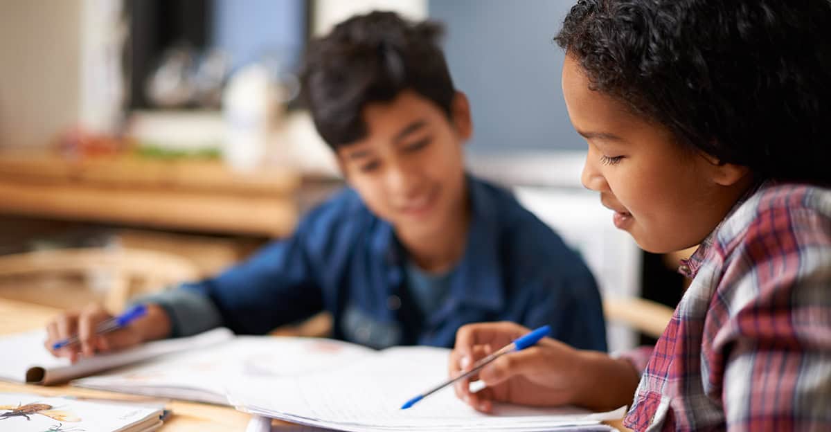 two students writing together at a desk