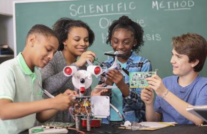 Junior high age students work on building a robot in technology class in school classroom setting.  STEM topics.