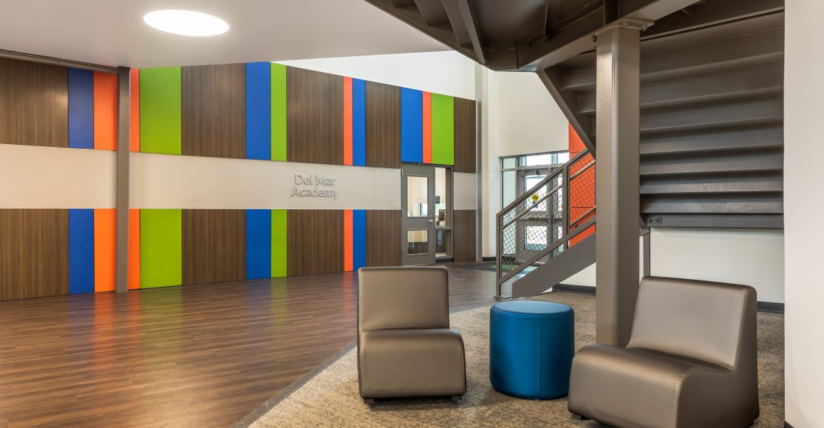 A colorful lobby of a school with two brown chairs and a side table.