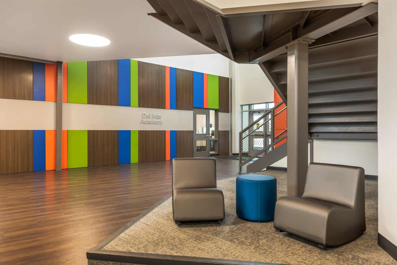 A colorful lobby of a school with two brown chairs and a side table.