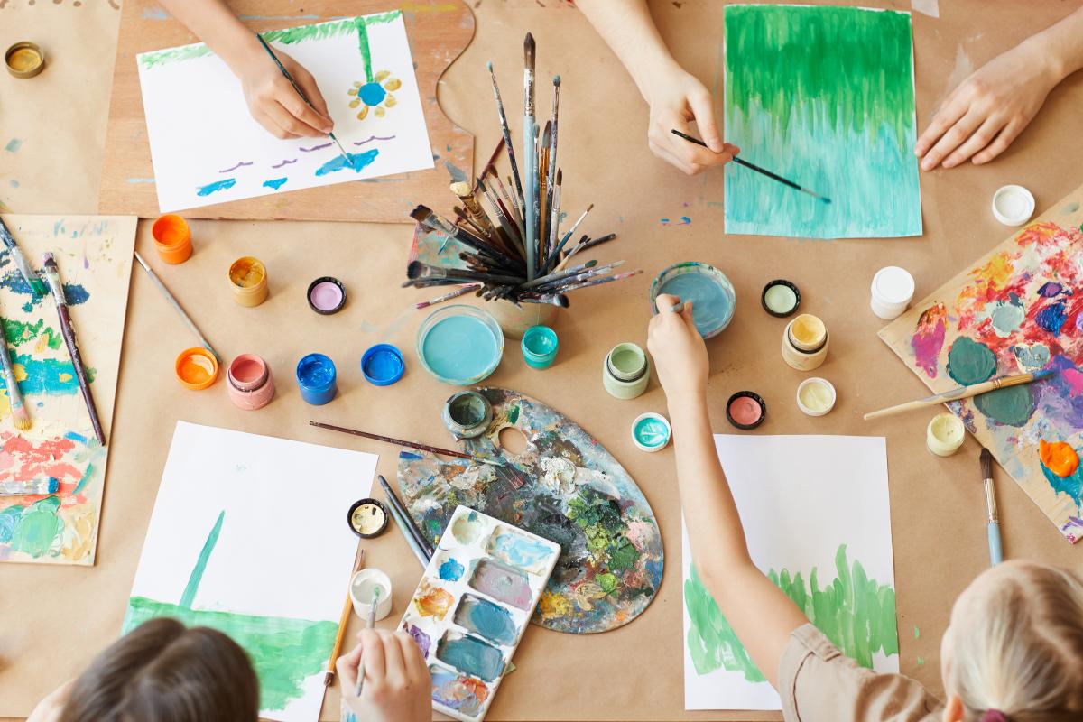 Vista de alto ângulo de um grupo de crianças pintando seus quadros com tintas aquarela durante a aula de arte