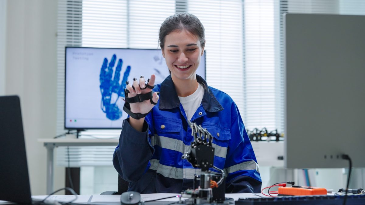 White Woman engineer developer in robotics arm prototype demonstrating a practical robotics in human-machine interaction controller and Checking Robotic parts Hardware and applied software