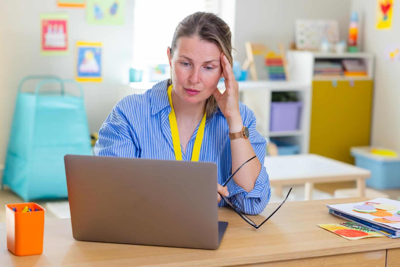 Woman working in daycare with laptop while stressed
